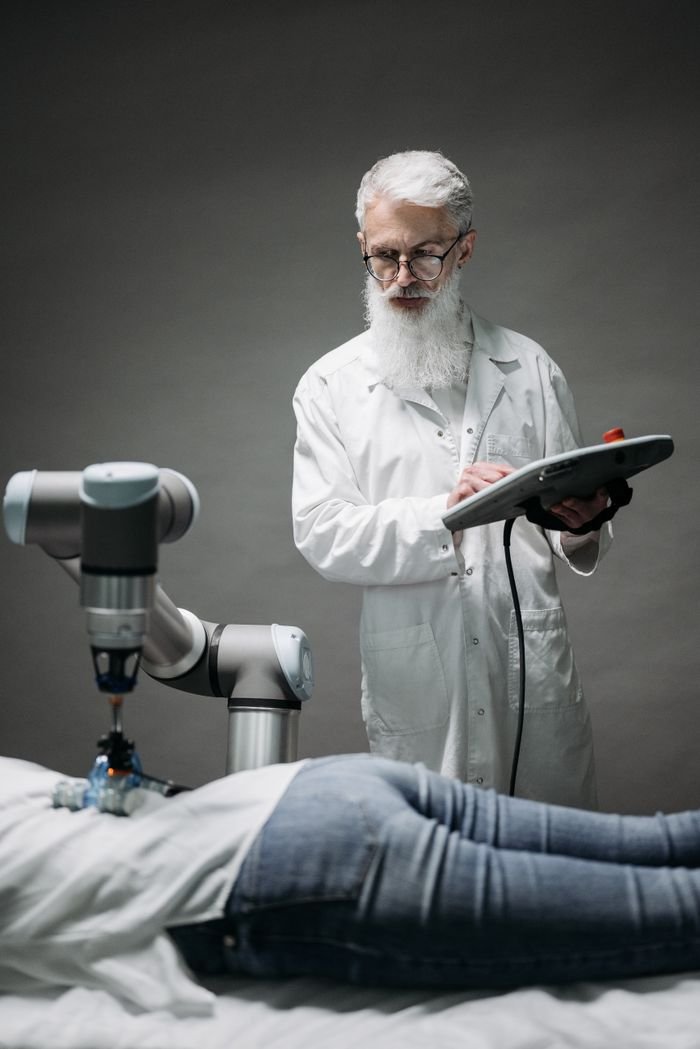 A senior scientist controls a robotic arm for medical applications in a lab setting.